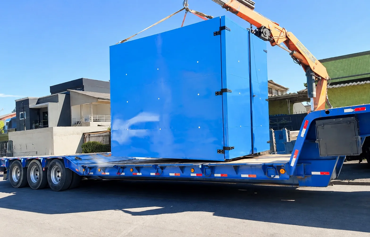 Equipamento industrial azul carregado em carreta