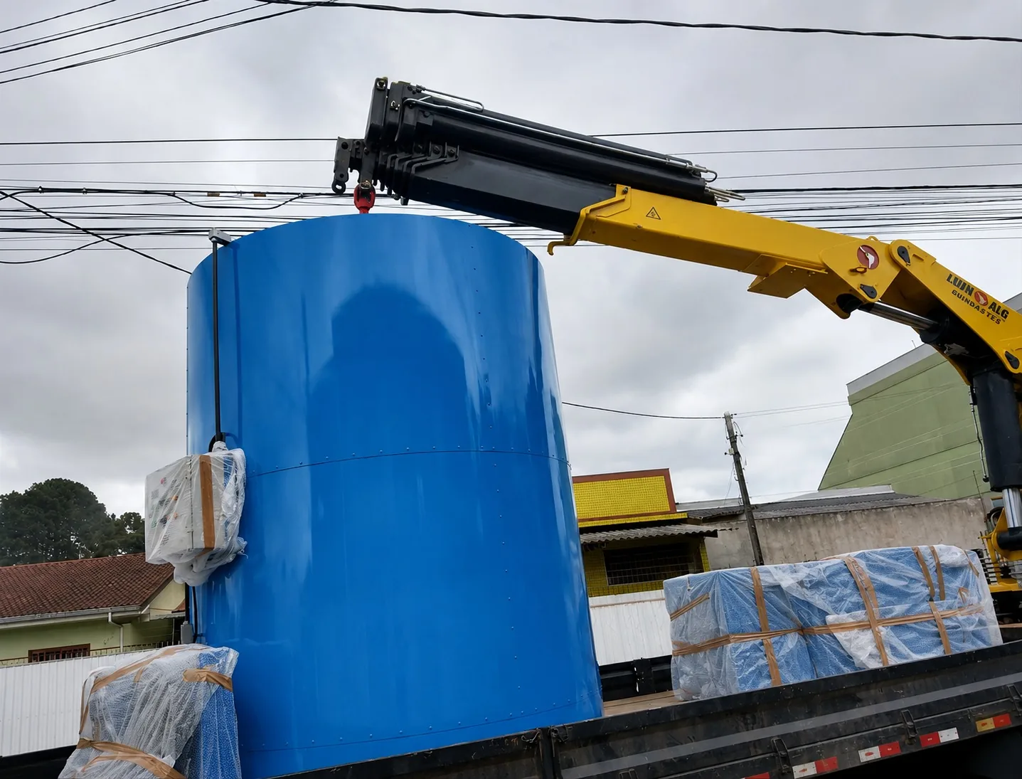 Tanque industrial azul sendo içado para transporte